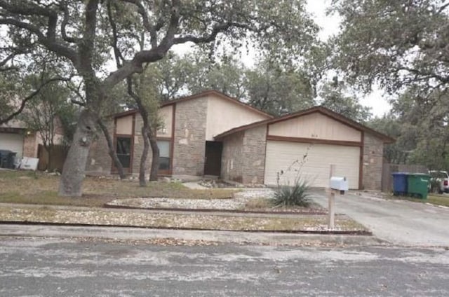 view of front of home with stone siding, a garage, and concrete driveway