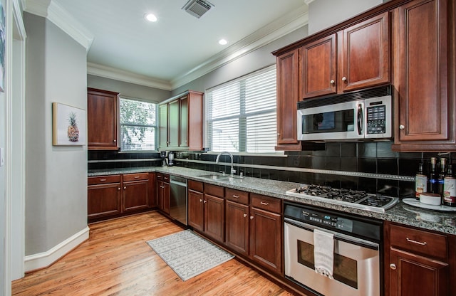 kitchen with stainless steel appliances, a sink, visible vents, light wood-style floors, and decorative backsplash