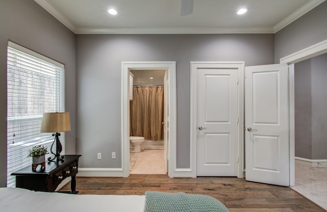 bedroom featuring ensuite bath, wood finished floors, baseboards, and crown molding
