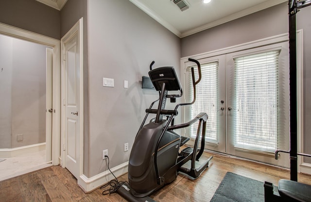 exercise room featuring wood finished floors, visible vents, crown molding, and baseboards