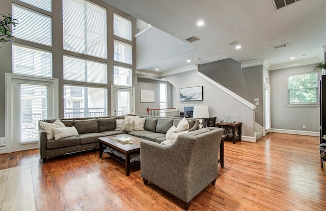 living room featuring crown molding, light wood-style flooring, and plenty of natural light