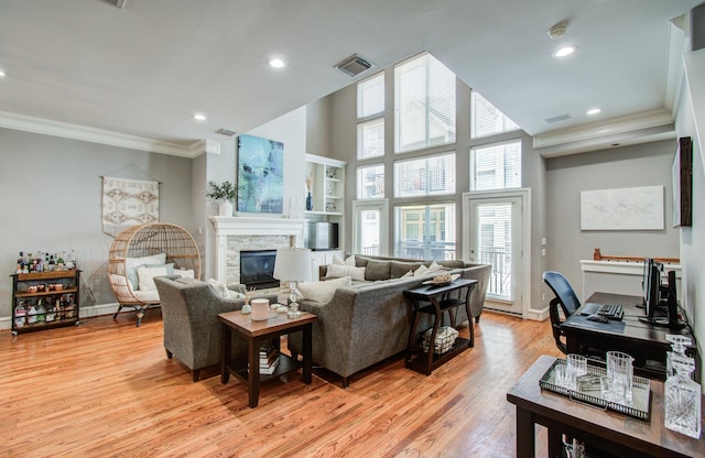 living room with visible vents, ornamental molding, light wood-type flooring, baseboards, and a fireplace