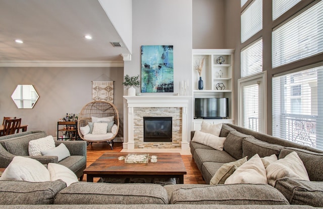living area featuring ornamental molding, wood finished floors, visible vents, and plenty of natural light