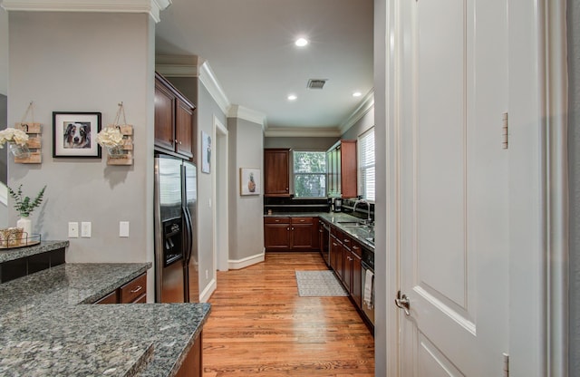 kitchen featuring crown molding, a sink, light wood-style floors, stainless steel appliances, and visible vents