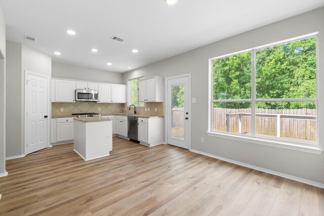 1020 Jefferson St, Alvin, TX 77511 - kitchen featuring white cabinets, stainless steel appliances, visible vents, a center island, and tasteful backsplash