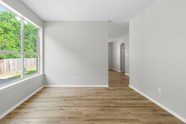 1020 Jefferson St, Alvin, TX 77511 - spare room featuring light wood-type flooring, baseboards, arched walkways, and a healthy amount of sunlight