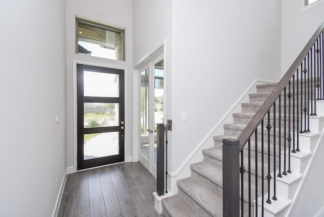 entryway with baseboards, wood finished floors, a towering ceiling, and stairs