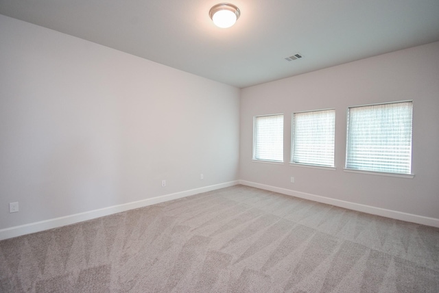 empty room featuring visible vents, baseboards, and light carpet