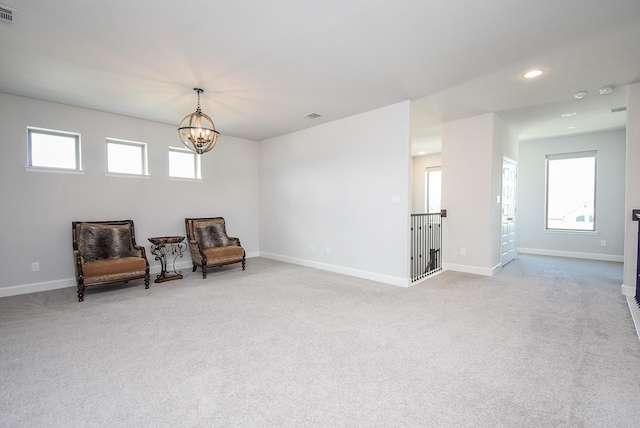 living area featuring a chandelier, carpet, visible vents, and baseboards