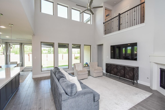 living area featuring a ceiling fan, baseboards, a wealth of natural light, and dark wood-type flooring