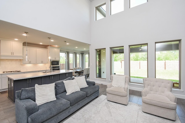 living room featuring light wood-style flooring and a towering ceiling