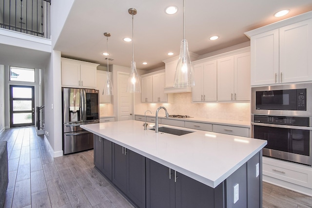 kitchen featuring light countertops, appliances with stainless steel finishes, white cabinetry, and a sink