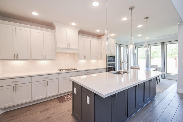 kitchen featuring a sink, light wood-type flooring, stainless steel appliances, white cabinets, and recessed lighting