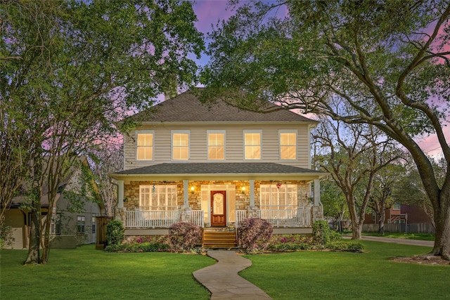 american foursquare style home with covered porch and a lawn
