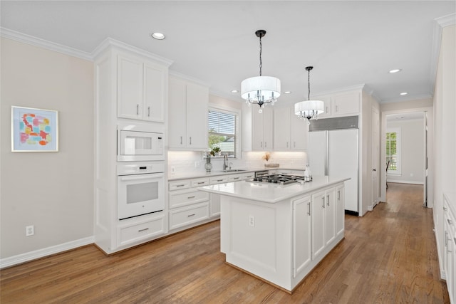 kitchen with built in appliances, a sink, recessed lighting, decorative backsplash, and light wood-type flooring