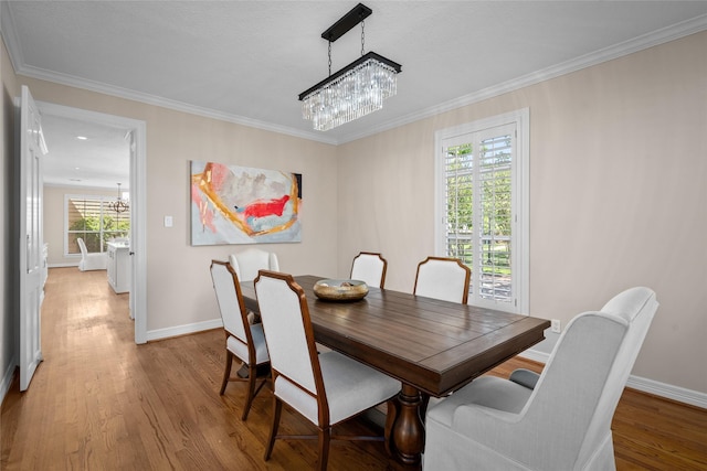 dining area with a chandelier, light wood-style floors, crown molding, and baseboards