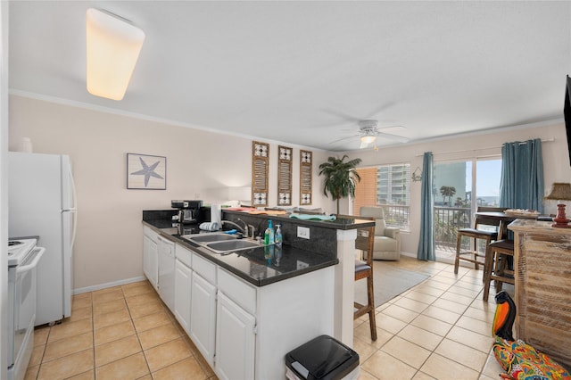 9520 Seawall Blvd Unit 226, Galveston, TX 77554 - kitchen featuring white cabinets, dark countertops, a sink, white appliances, and a peninsula