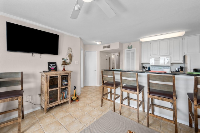 9520 Seawall Blvd Unit 226, Galveston, TX 77554 - kitchen with a kitchen breakfast bar, dark countertops, visible vents, white microwave, and ceiling fan
