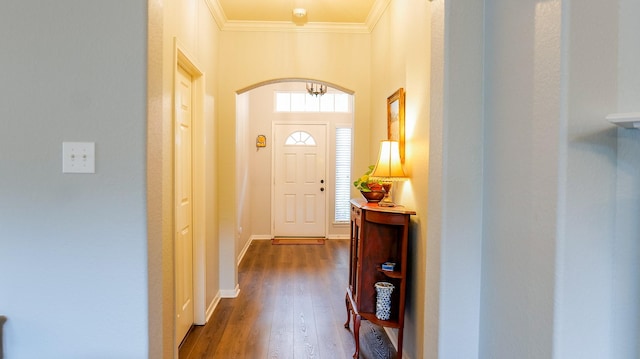 doorway with arched walkways, dark wood-style flooring, baseboards, and ornamental molding