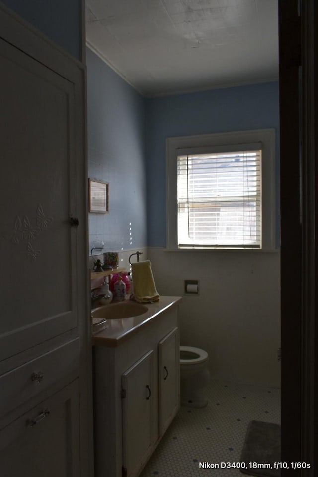 half bath with tile patterned flooring, toilet, and vanity