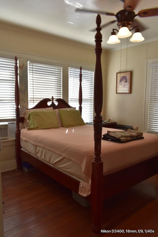 bedroom featuring crown molding, wood finished floors, and multiple windows