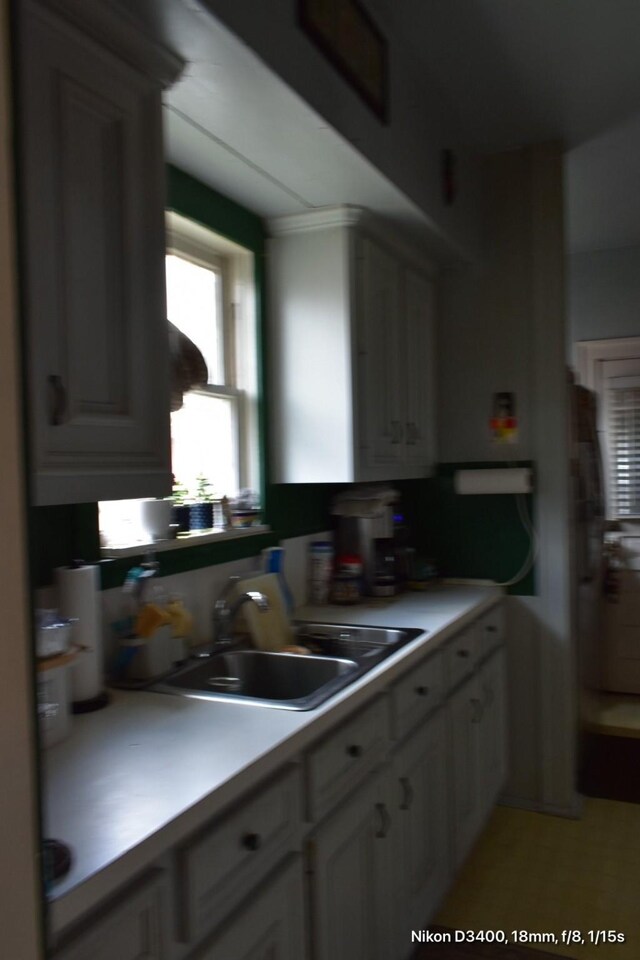 kitchen featuring white cabinetry, a sink, and light countertops
