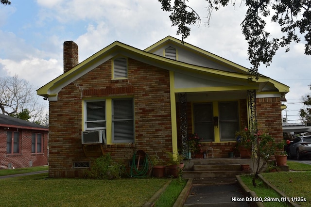 bungalow with a chimney, brick siding, a front yard, and cooling unit