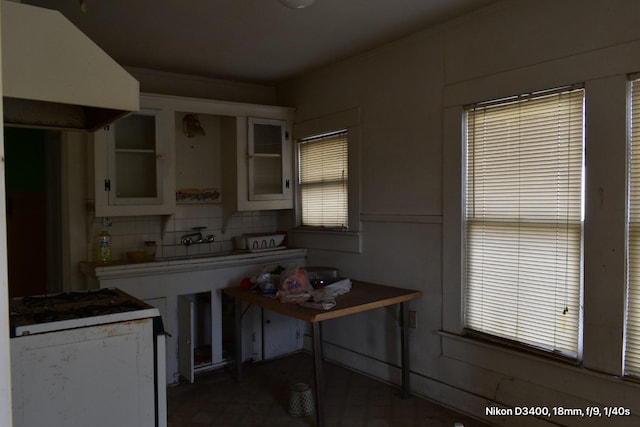 kitchen featuring white cabinets, glass insert cabinets, tasteful backsplash, and exhaust hood