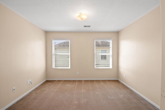 empty room with visible vents, baseboards, and light carpet
