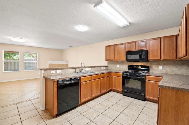 kitchen with light tile patterned floors, a sink, black appliances, a peninsula, and a textured ceiling
