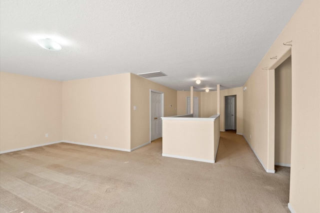 spare room featuring light colored carpet, baseboards, and a textured ceiling