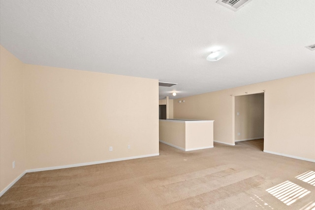 empty room featuring baseboards, visible vents, and light colored carpet