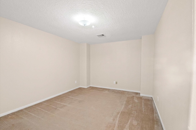 empty room featuring a textured ceiling, visible vents, baseboards, and light carpet