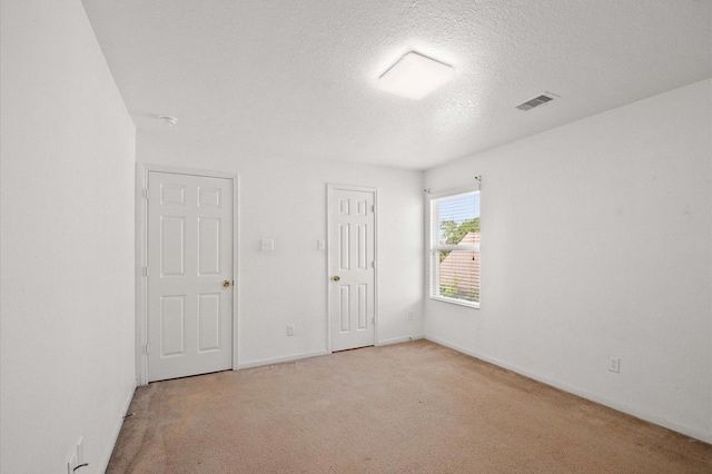 spare room featuring baseboards, visible vents, carpet floors, and a textured ceiling