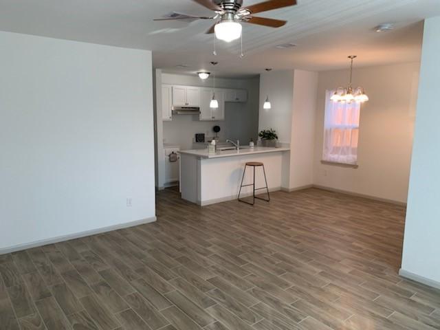4533 Rosemont St, Houston, TX 77051 - kitchen featuring wood finished floors, ceiling fan with notable chandelier, light countertops, baseboards, and a peninsula