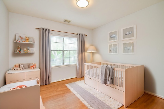 3911 Fallsbrook Ct, Sugar Land, TX 77479 - bedroom with baseboards, light wood-style flooring, visible vents, and a nursery area