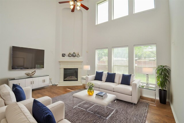 3911 Fallsbrook Ct, Sugar Land, TX 77479 - living area featuring wood finished floors, a glass covered fireplace, ceiling fan, a towering ceiling, and baseboards