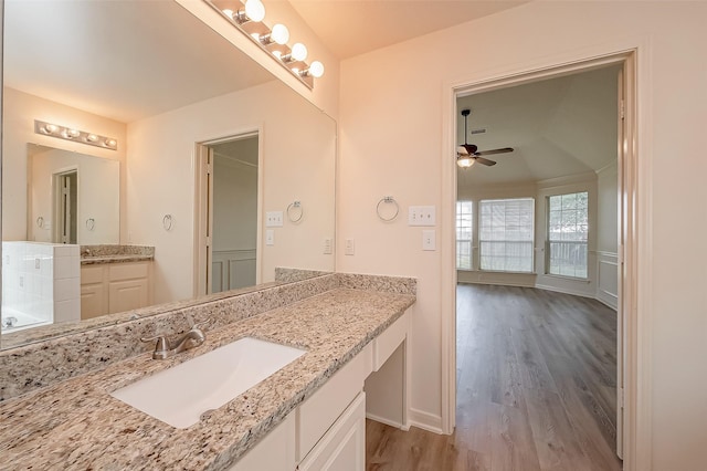 bathroom featuring ceiling fan, two vanities, wood finished floors, and a sink