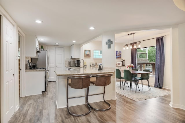 224 Clear Lake Rd, Clear Lake Shores, TX 77565 - kitchen featuring a kitchen bar, white cabinets, wood finished floors, and a sink