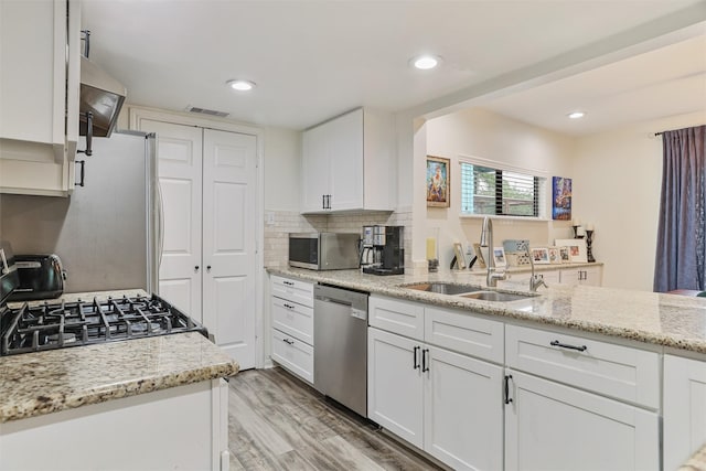 224 Clear Lake Rd, Clear Lake Shores, TX 77565 - kitchen with light stone counters, a sink, light wood finished floors, white cabinetry, and appliances with stainless steel finishes