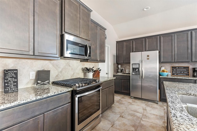 22086 Sun Haven Ln, Porter, TX 77365 - kitchen featuring vaulted ceiling, light stone counters, dark brown cabinetry, stainless steel appliances, and backsplash