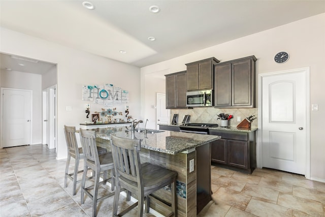 22086 Sun Haven Ln, Porter, TX 77365 - kitchen featuring stainless steel appliances, stone counters, dark brown cabinetry, backsplash, and an island with sink
