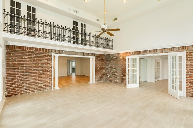 2610 Gerol Ct, Galveston, TX 77551 - unfurnished living room featuring brick wall, a high ceiling, a ceiling fan, and french doors
