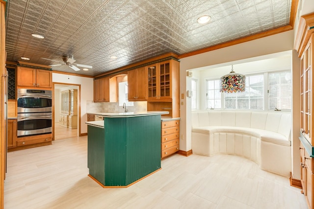 2610 Gerol Ct, Galveston, TX 77551 - kitchen with double oven, light countertops, brown cabinetry, ornamental molding, and glass insert cabinets