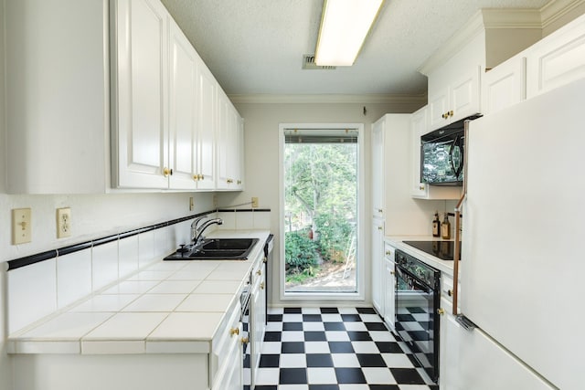 2610 Gerol Ct, Galveston, TX 77551 - kitchen with tile patterned floors, a sink, tile countertops, black appliances, and white cabinets