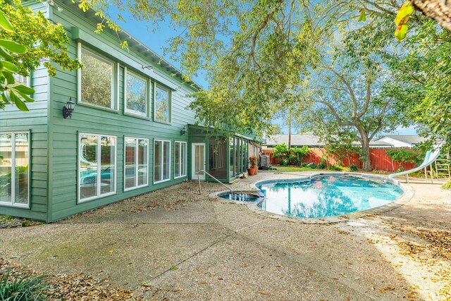 2610 Gerol Ct, Galveston, TX 77551 - view of pool featuring a pool with connected hot tub, a patio area, a water slide, and a fenced backyard