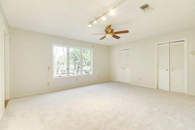 2610 Gerol Ct, Galveston, TX 77551 - unfurnished bedroom with visible vents, light colored carpet, ceiling fan, two closets, and rail lighting