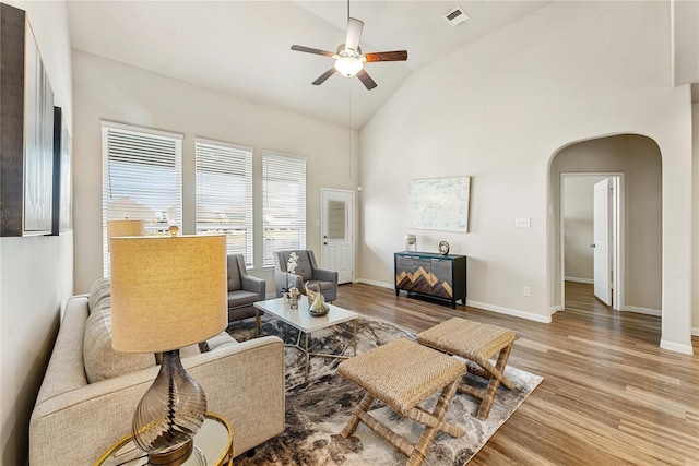 living room featuring visible vents, a ceiling fan, arched walkways, baseboards, and light wood-style flooring