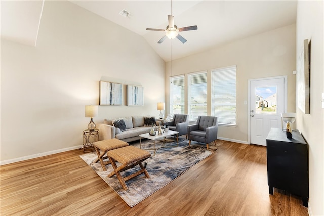 living area with high vaulted ceiling, a ceiling fan, light wood-type flooring, baseboards, and visible vents