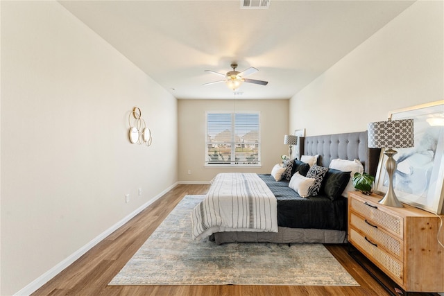 bedroom featuring wood finished floors, visible vents, baseboards, and ceiling fan